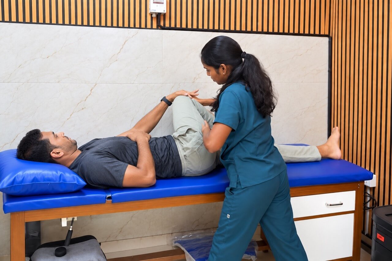 Physiotherapist assisting a bent-knee movement on a treatment bed